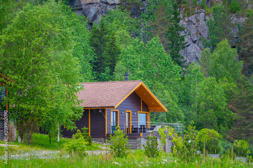 Cottage. The house is on the background of a mountain. Cottage in the country. The house is surrounded by greenery.