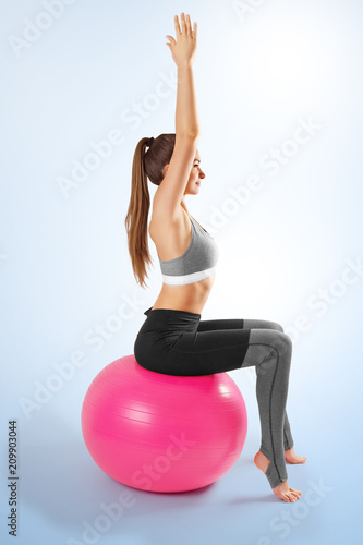 Pilates and fitness sport girl in yoga fitness exercise on the floor, indoor training sitting on the pink pilates ball. Healthy lifestyle. Yoga position photo