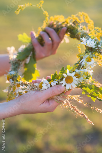 Midsummer in Latvia: celebration of Ligo - a young woman weave a wreath and collect field flowers