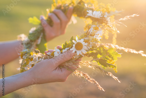 Midsummer in Latvia: celebration of Ligo - a young woman weave a wreath and collect field flowers