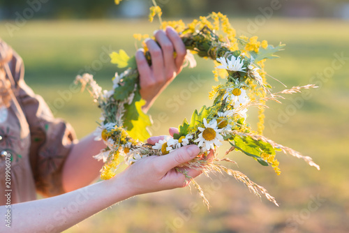 Midsummer in Latvia: celebration of Ligo - a young woman weave a wreath and collect field flowers