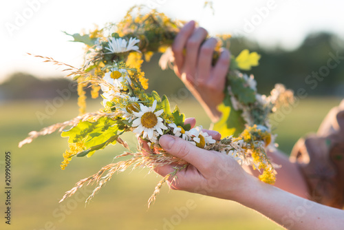 Midsummer in Latvia: celebration of Ligo - a young woman weave a wreath and collect field flowers © elinque