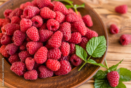 Tasty juicy sweet raspberry on a wooden background. It can be used as a background