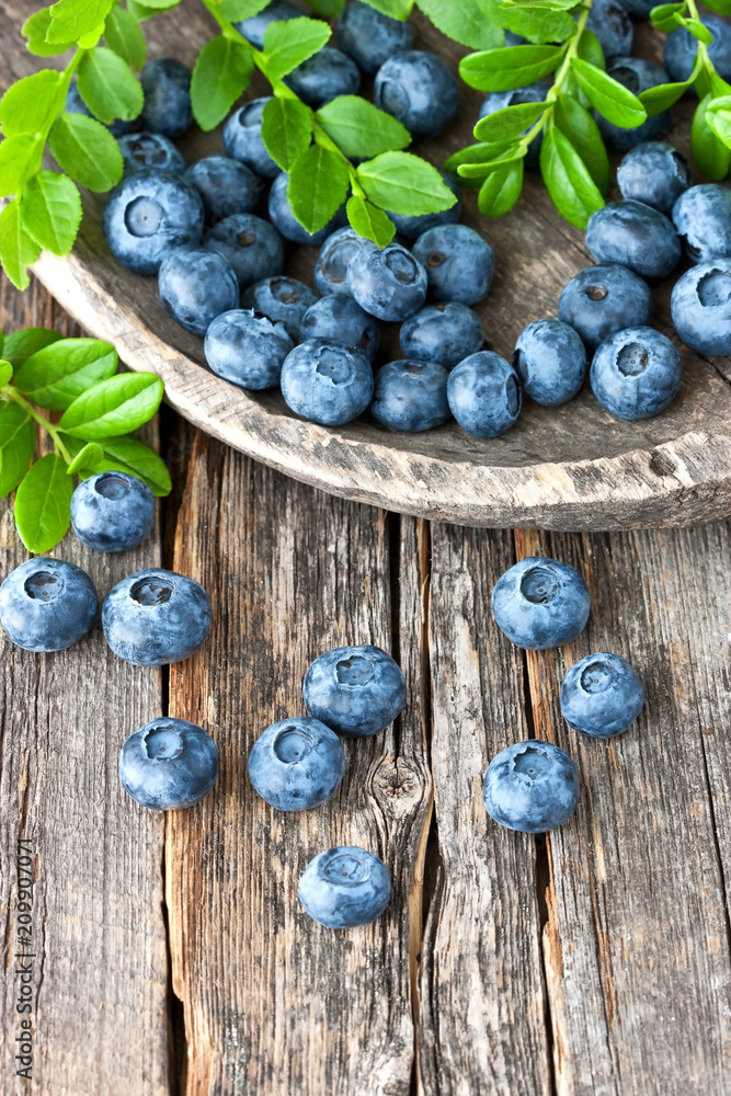 Blueberries with green leaves on old wooden surface Blueberries with green leaves on old wooden surface