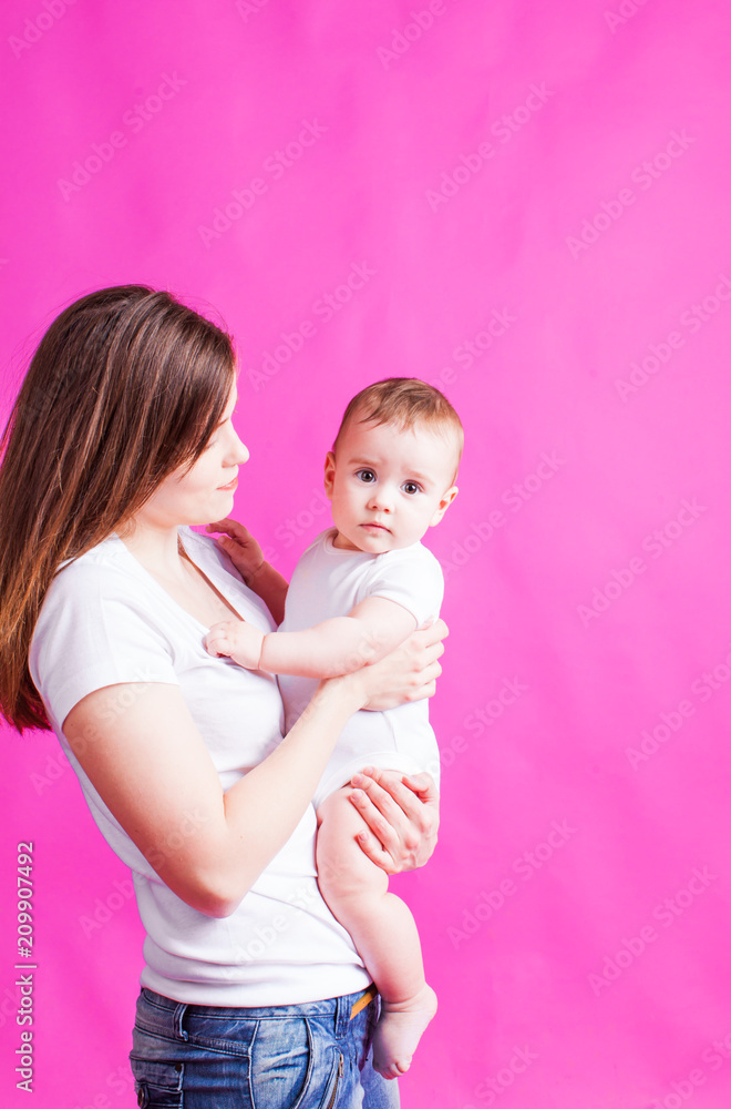 Young mother holding her baby, on a pink background Young mother holding her baby, on a pink background