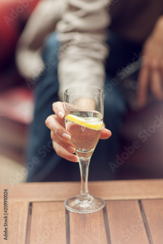 Young woman drinking a glass of water in a street cafe, close up on her hand holding glass, sunny urban mood