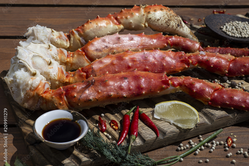 Fresh crab claws with sauce, pepper and lemon on vintage wooden background. 
