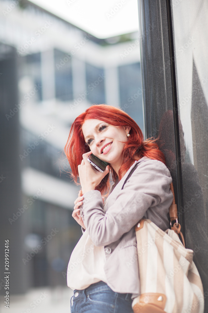 Fototapeta premium young beautiful business woman holdingmobile phone, working in downtown, outdoors