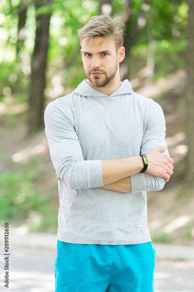 Confident sportsman. Runner workout outdoor in park. Man athlete with smart watch running outdoor, nature background. Athletic confident man trainer. Athlete guy coach watching confidently Confident sportsman. Runner workout outdoor in park. Man athlete with smart watch running outdoor, nature background. Athletic confident man trainer. Athlete guy coach watching confidently