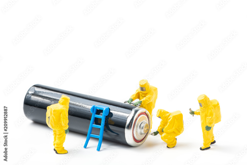 The figurines in protective suit examine a used battery isolated on white background The figurines in protective suit examine a used battery isolated on white background