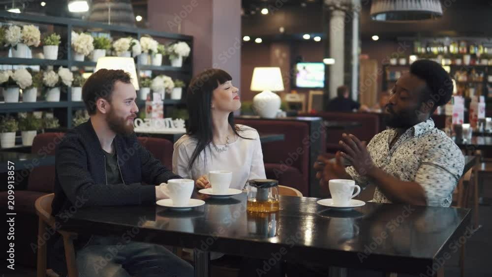 multi-ethnic company of friends in a cafe or restaurant. friends talk and have fun together. multi-ethnic company of friends in a cafe or restaurant. friends talk and have fun together.