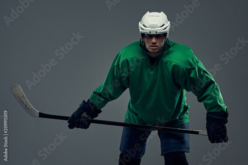 Photography Portrait of a professional hockey player wearing full gear and a hockey stick on a gray background