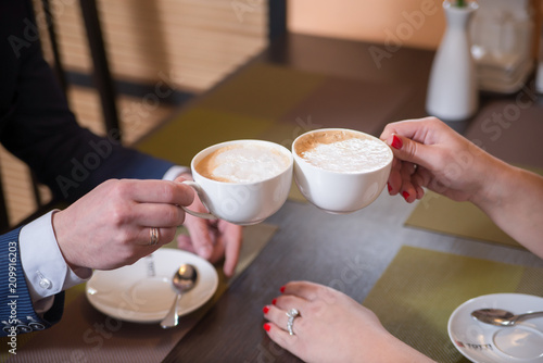 A couple drinking coffee together in restaurant. Crop on hands