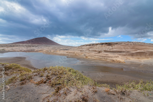 Landscape of a mountain and a lake, with some storm clouds. Views of the Médano in Tenerife, Canary Islands.