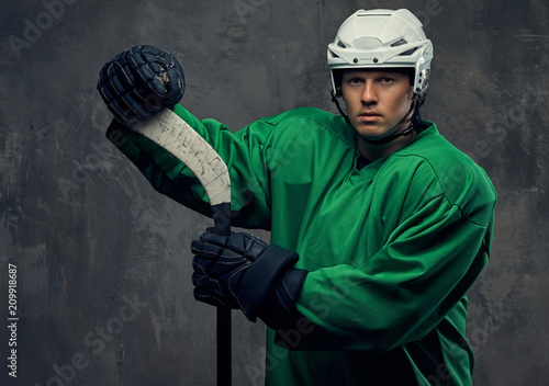 Photography Hockey player wearing green protective gear and white helmet standing with the hockey stick