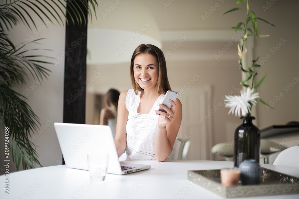 Smiling woman using a smartphone and a laptop Smiling woman using a smartphone and a laptop