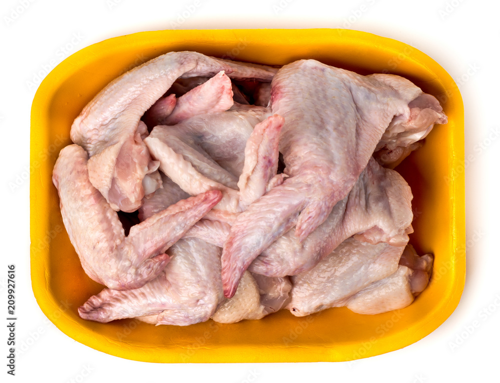 Raw chicken wings in plastic packaging, on a white. The view from the top. Raw chicken wings in plastic packaging, on a white. The view from the top.