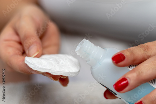 Woman removes red nail polish with nail polish remover