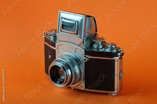 The old 35 mm SLR camera on a orange background. photo