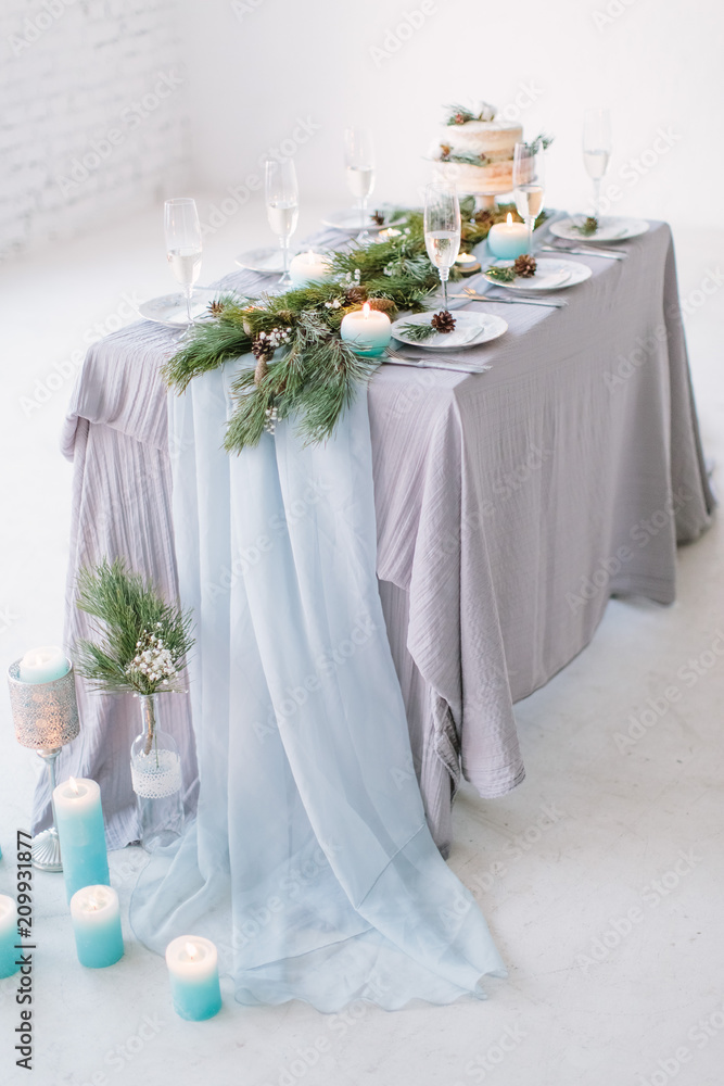 Wedding. Banquet. The chairs and table for guests, decorated with candles, served with cutlery and crockery and covered with a tablecloth.