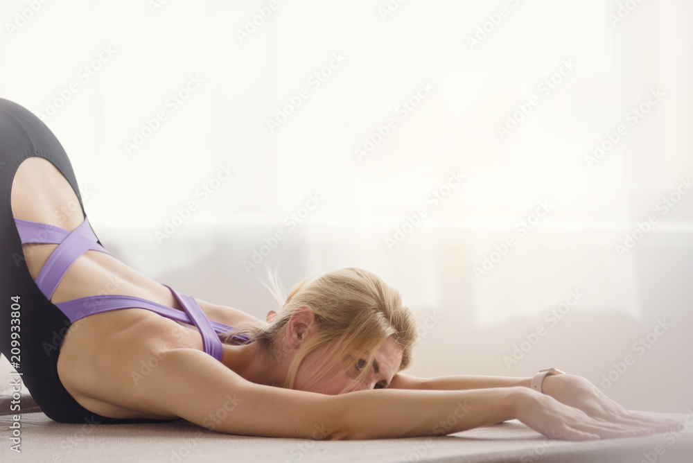Obraz premium Healthy young woman stretching her body and lying on mat