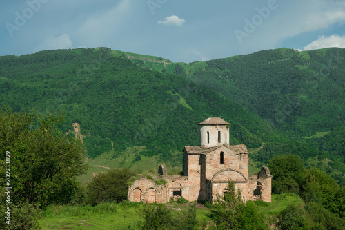 the ancient Christian Sentinian temple of the 10th century in the Karachay-Cherkess Republic against the background of green, overgrown mountains.