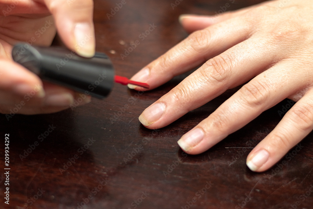 Woman vanishing her finger nails with red enamel