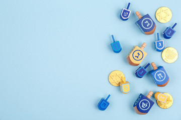Blue background with multicolor dreidels and chocolate coins. Hanukkah and judaic holiday concept.