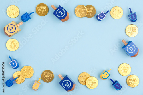 Blue background with multicolor dreidels and chocolate coins. Hanukkah and judaic holiday concept.