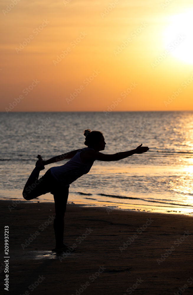 Silhouette of woman practicing yoga at seashore