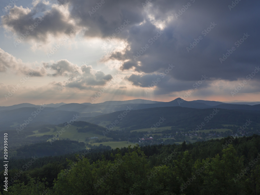 Lusatian Mountains (luzicke hory) panorama,view from Hochwald (Hvozd) mountain on czech german borders with sun rays blue green hills forest and pink cloudy sunset sky background