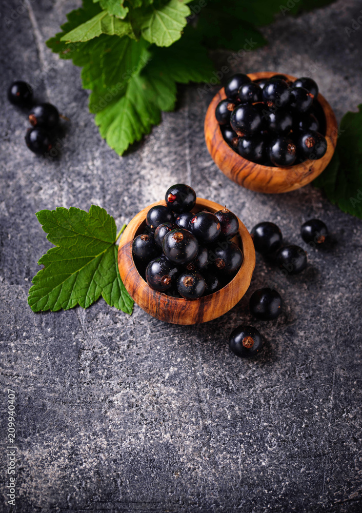 Black currant with leaves in wooden bowls Black currant with leaves in wooden bowls