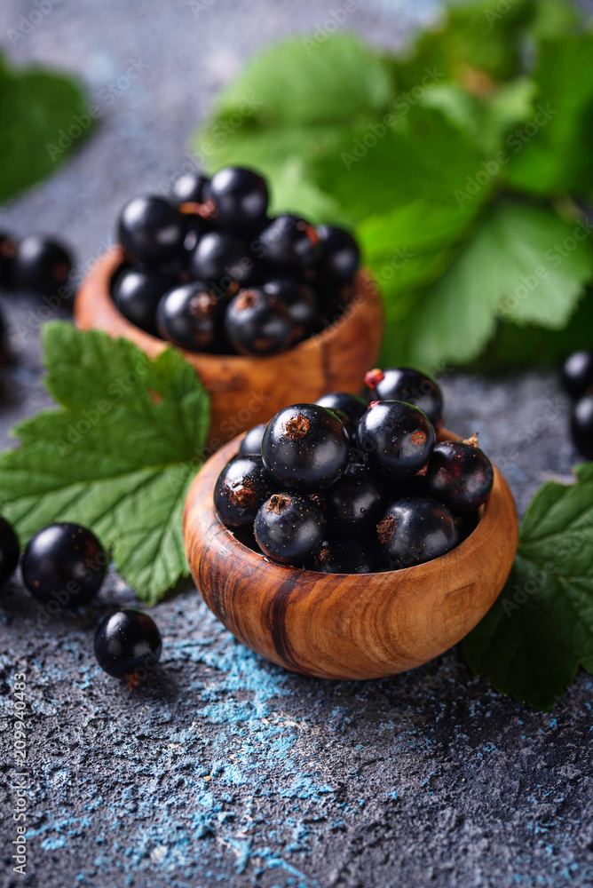 Black currant with leaves in wooden bowls