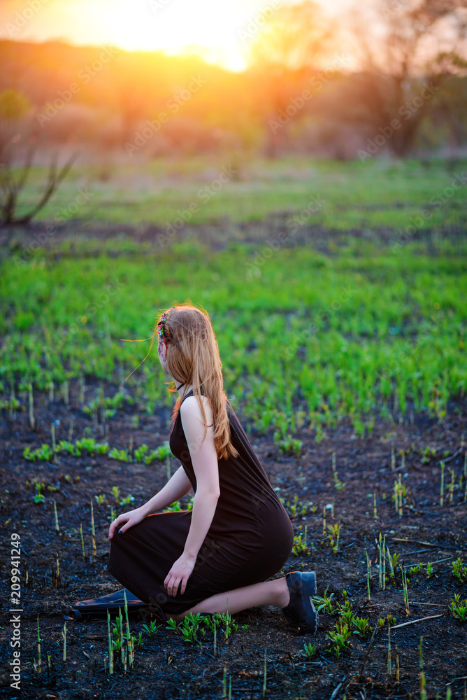 Young beautiful woman with purple shine on her face standing on the grass and looking at the back