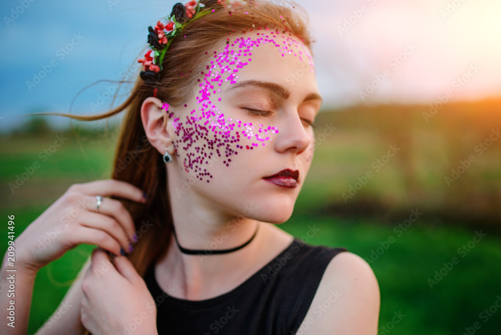 A young beautiful woman with a violet shine on her face standing on the grass and looking right