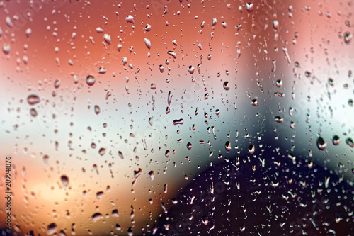 Water rain drops on the window glass on sunset. Shallow depth of field. Cityscape silhouette.