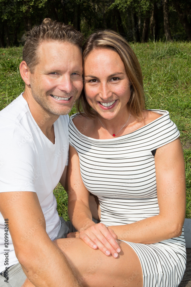 Middle-aged couple embracing in front of house in garden park Middle-aged couple embracing in front of house in garden park