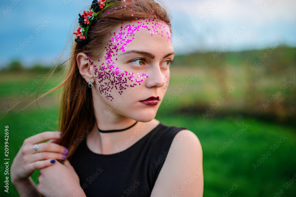 A young beautiful woman with a violet shine on her face standing on the grass and looking right