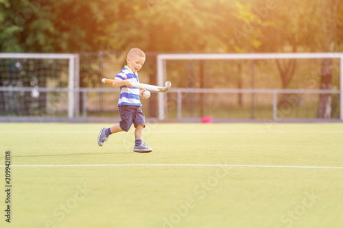 Small boy training playing field hockey with stick on the field © skumer