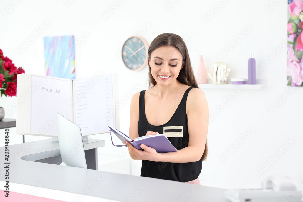 Beauty salon receptionist with notebook at desk Beauty salon receptionist with notebook at desk