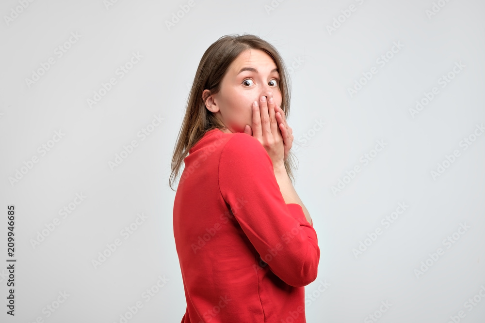 Upset girl in red sweater holding her hands on her chin being scared after what she did. Upset girl in red sweater holding her hands on her chin being scared after what she did.