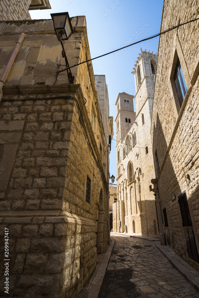 A narrow alley in Giovinazzo old town, with the Cathedral on the right, Apulia, Italy