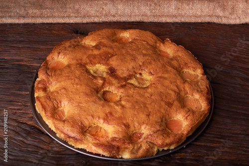 Tart with apricots on wooden table background close up