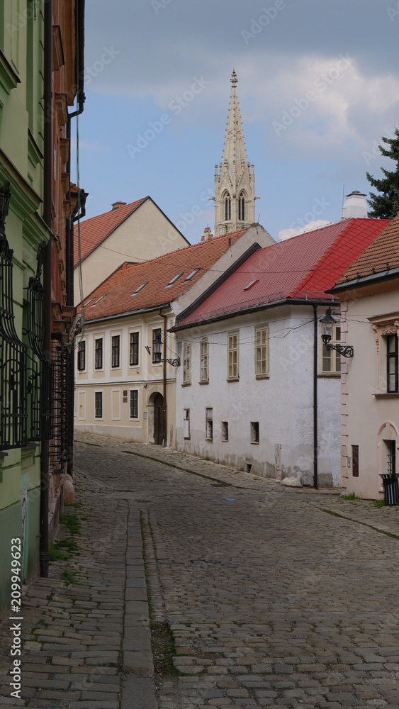 Obraz premium Cobblestone Street with Historic Church Spire in Bratislava Old Town