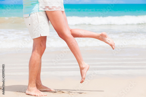 legs of young hugging couple on tropical turquoise beach