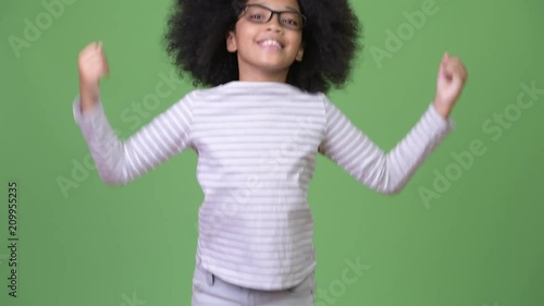 Young cute African girl with Afro hair looking happy and excited while jumping