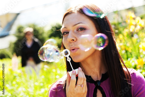 girl blow soap bubble against a background grass