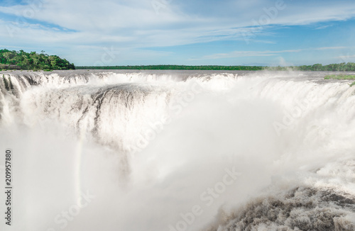 Wide angle landscape view of Iguazu waterfalls on a sunny day in summer. Photo taken from the Argentinian side at the Devil’s throat.