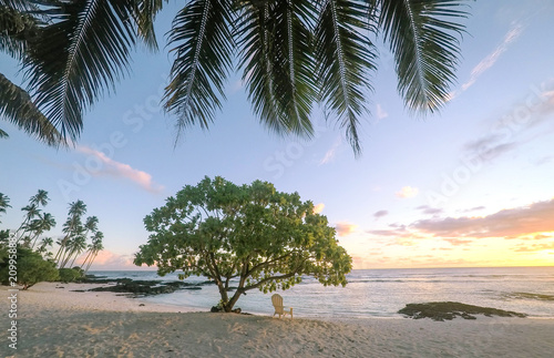 Sunset on beautiful empty tropical beach with deckchair and palm tree fronds at Lefaga, Matautu, Upolu Island, Samoa, South Pacific photo