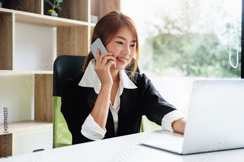 Asia business accounting concept, woman using smart phone and laptop computer in office.